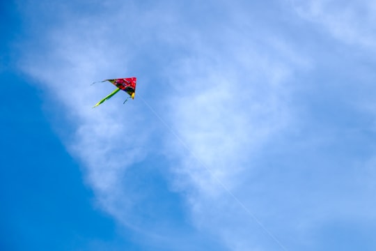 red and green kite flying under blue sky during daytime in Melaka Malaysia