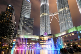 A cinematic shot of a bustling Kuala Lumpur street, neon lights blending into the night.