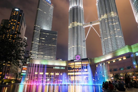 people walking on street near high rise buildings during night time in KLCC Park Malaysia