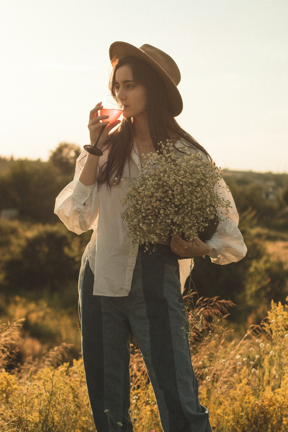 woman in white long sleeve shirt and black pants holding bouquet of flowers