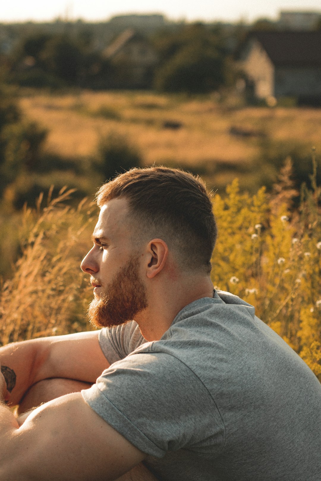 man in grey t-shirt sitting on ground during daytime