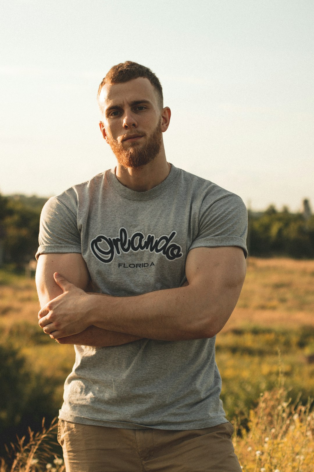 man in gray crew neck t-shirt standing on green grass field during daytime