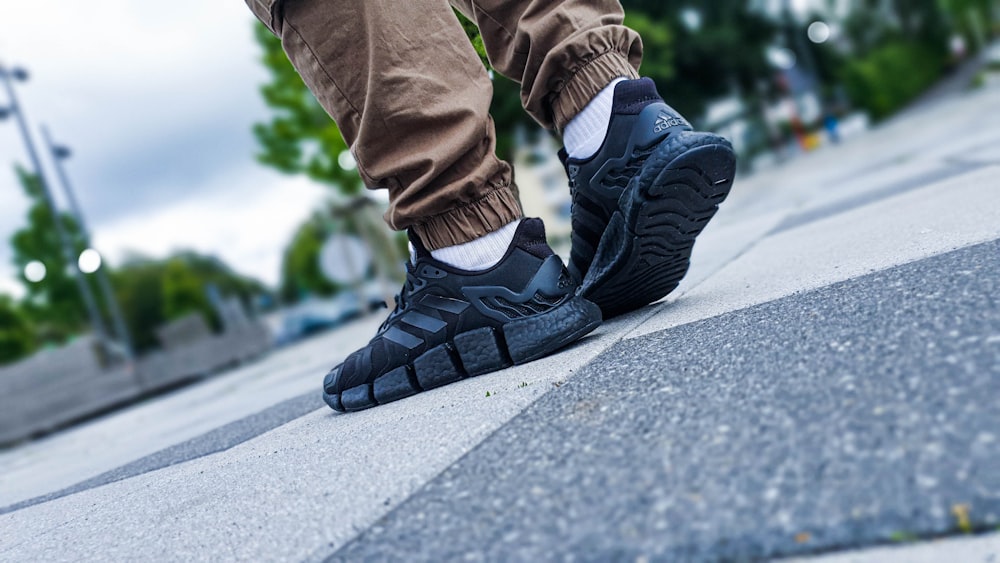 person in brown pants and black and white nike sneakers