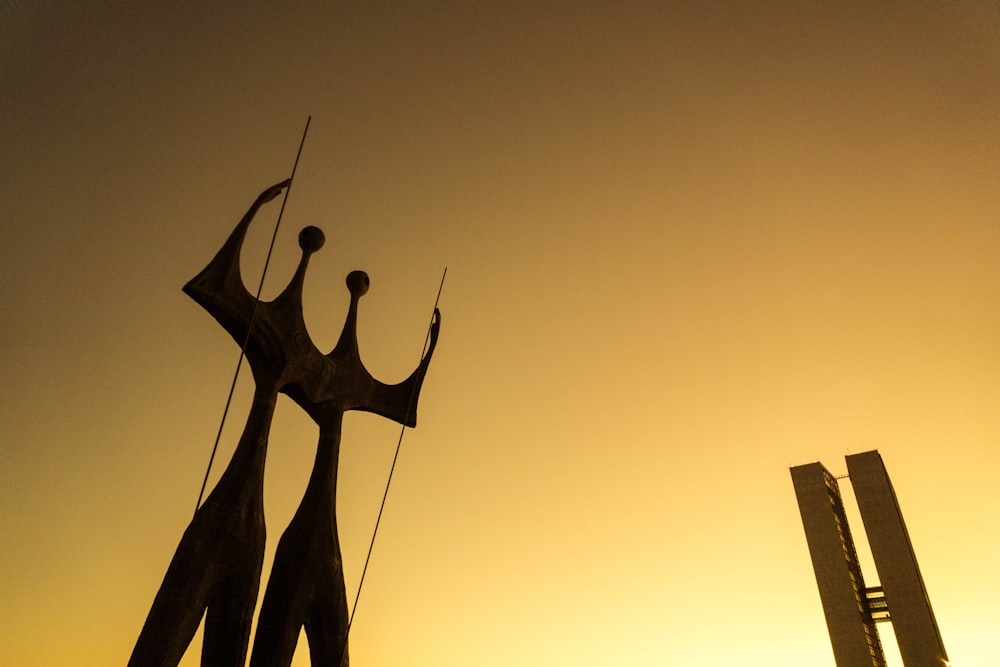 silhouette of two birds on top of building during sunset