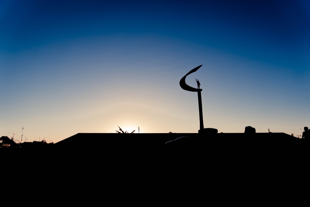 silhouette of person standing on top of building during sunset