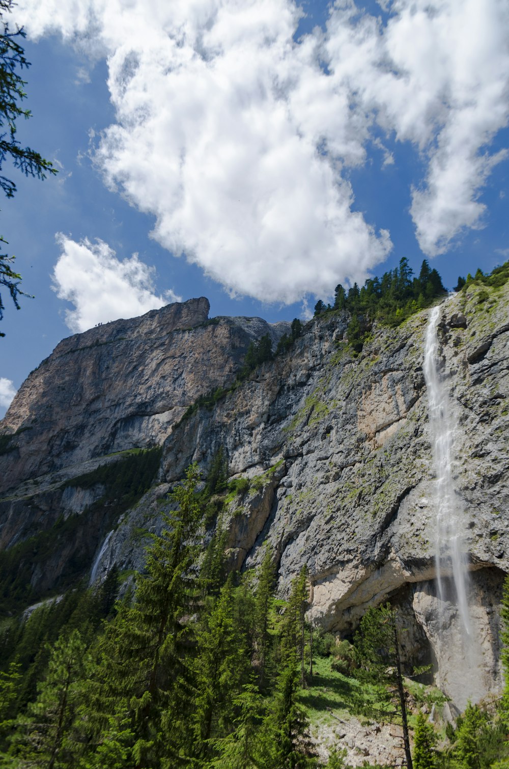 waterfalls on rocky mountain under blue and white cloudy sky during daytime