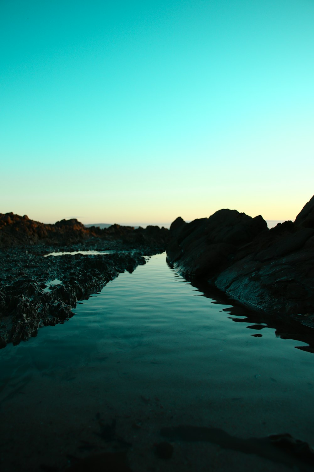 body of water near mountain during daytime