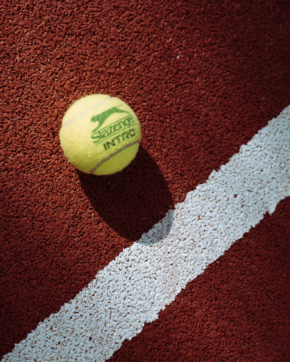 green tennis ball on red and white textile