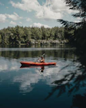 person riding red kayak on lake during daytime