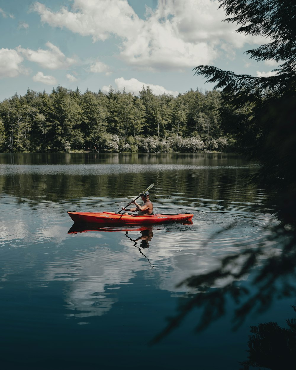person riding red kayak on lake during daytime