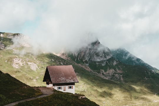 black and white house on green grass field near mountain under white clouds during daytime in Flums Switzerland