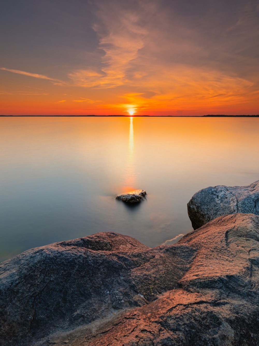 Formation rocheuse grise près d’un plan d’eau au coucher du soleil