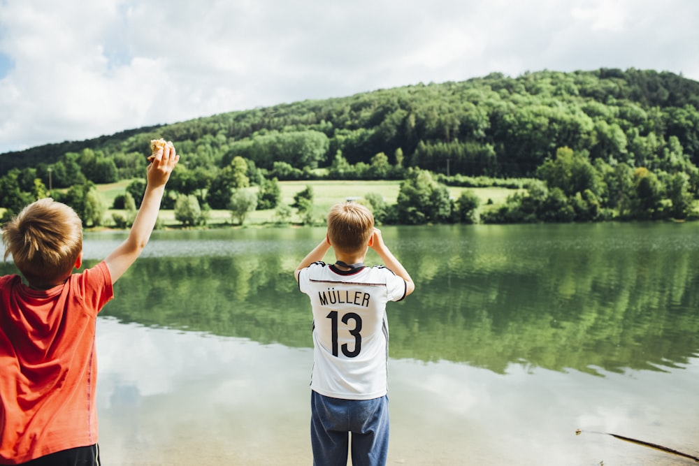 woman in white t-shirt and blue shorts standing on lake during daytime