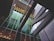 Modern architectural structure featuring geometric lines and a mix of reflective glass surfaces. The building includes vertical and horizontal elements with vibrant green panels contrasting against a predominantly grey and metallic color scheme.