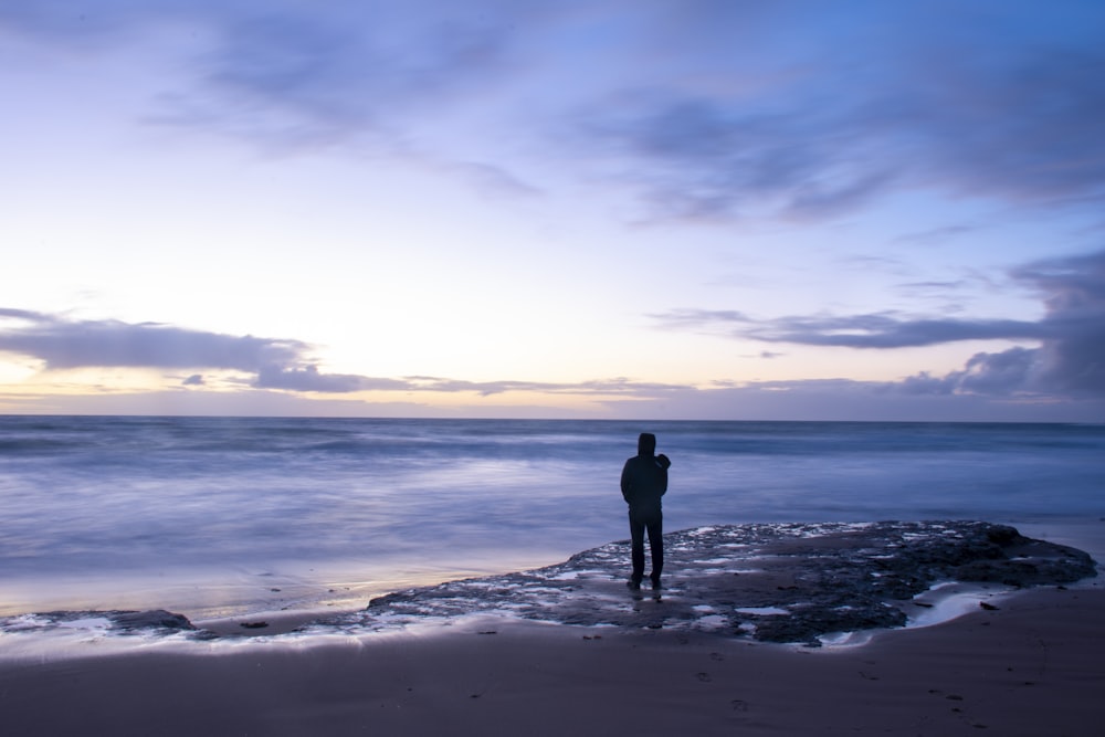 낮 동안 해변 해안에 서 있는 남자