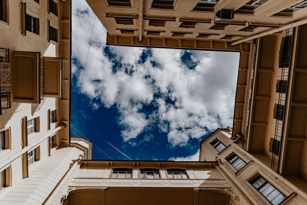 worms eye view of brown concrete building under blue and white cloudy sky during daytime