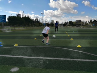 Young soccer player practicing ball control with coach Lauren on a sunny field.