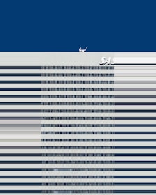 A tall building with horizontal stripes at the front, a deep blue sky in the background, and the letters SAS visible near the top of the building.