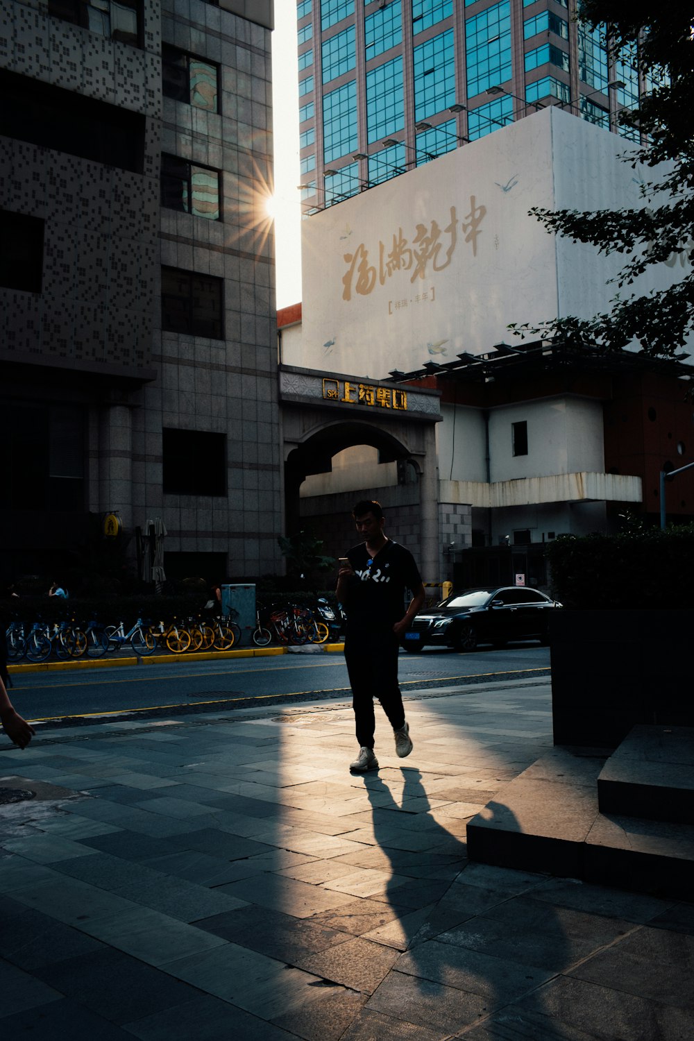 man in black jacket and black pants walking on sidewalk during daytime