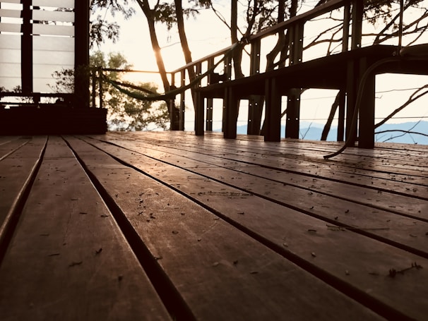 A warm wooden deck illuminated gently at dusk, overlooking the flowing Río Putagán surrounded by deep forest.