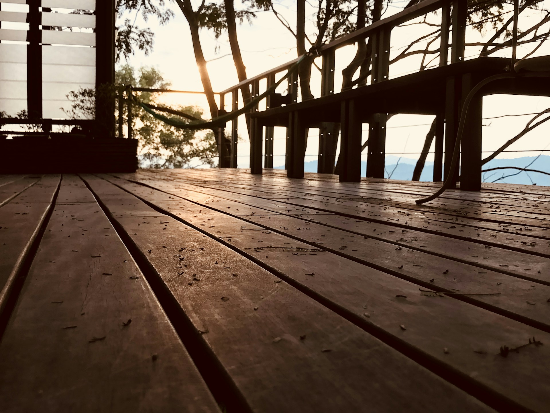A spacious modern deck with sleek wooden planks and built-in seating, bathed in warm afternoon sunlight.