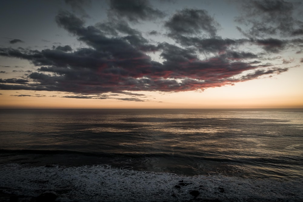 ocean waves crashing on shore during sunset