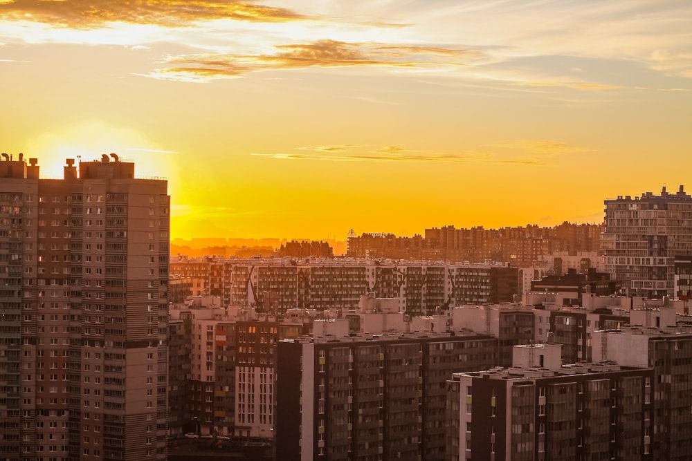 city skyline under orange and white cloudy sky during sunset