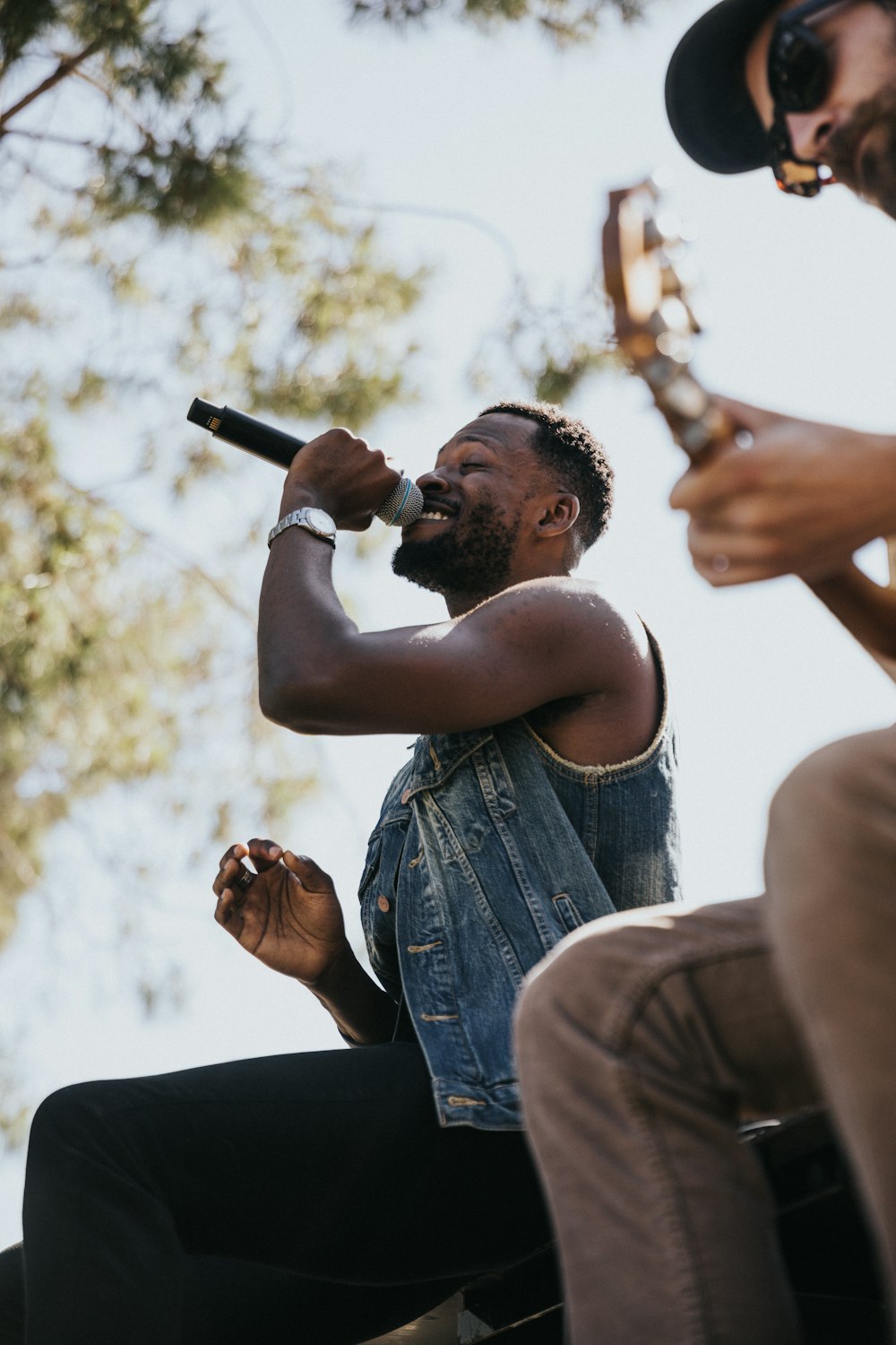 man in blue denim button up vest holding microphone