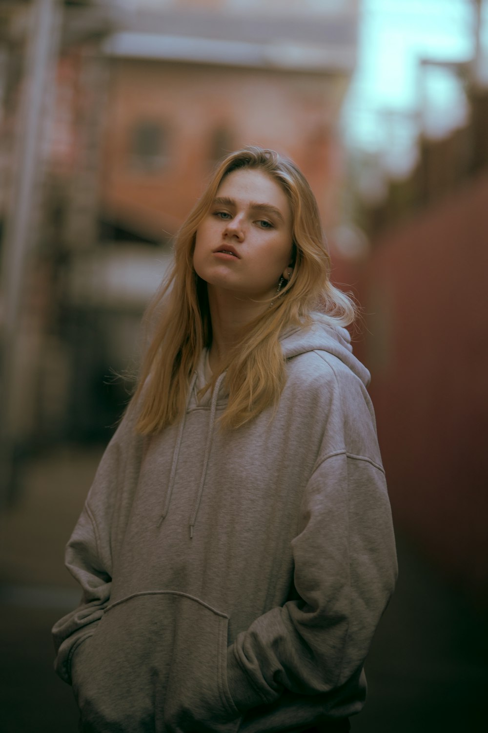 woman in gray hoodie standing near red wall