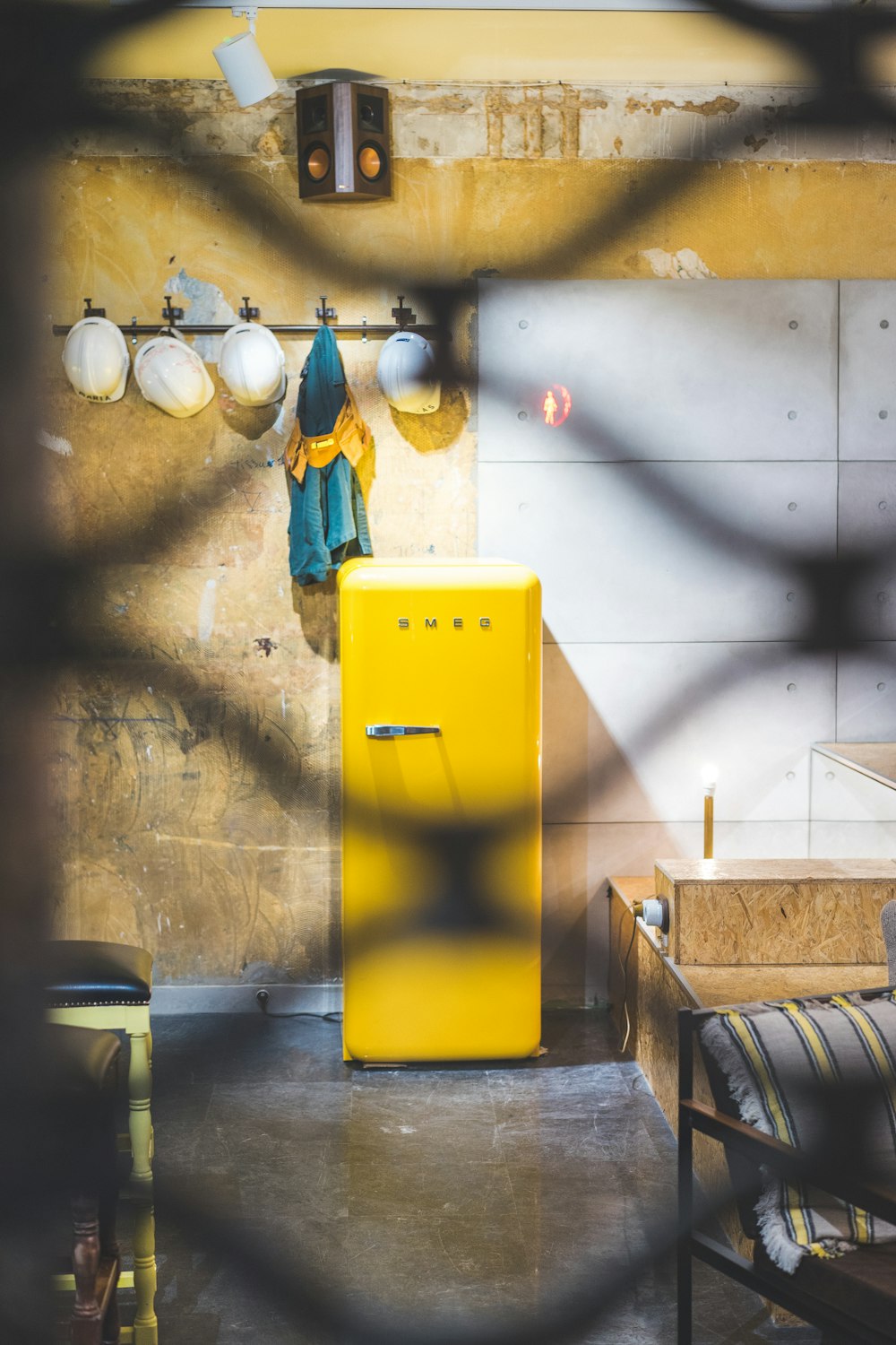 yellow plastic trash bin beside white wall