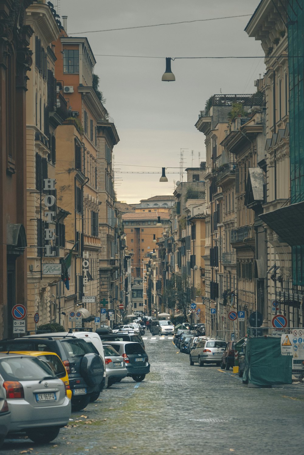 cars parked on street in between buildings during daytime