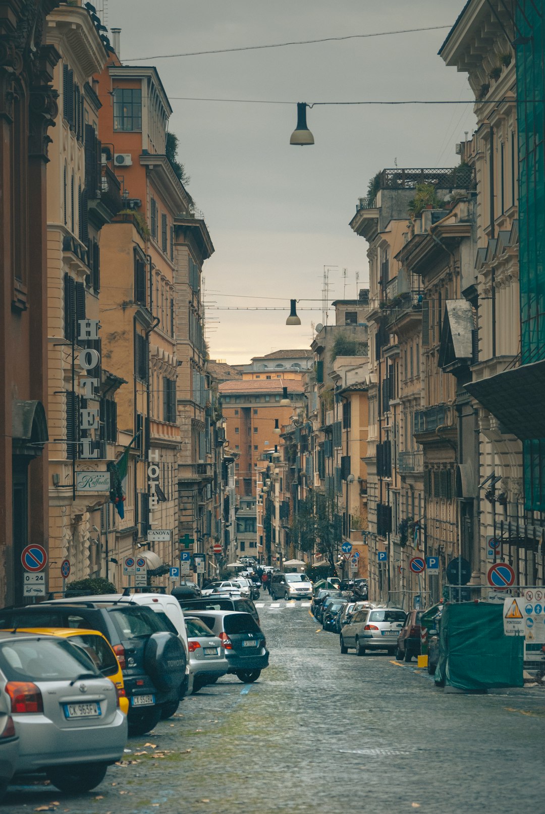 cars parked on street in between buildings during daytime