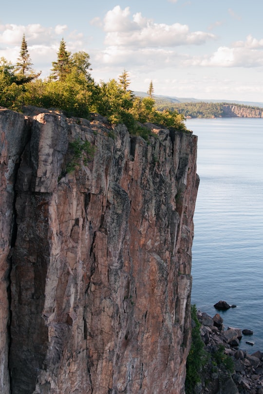 person sitting on rock formation near body of water during daytime in Palisade Head United States