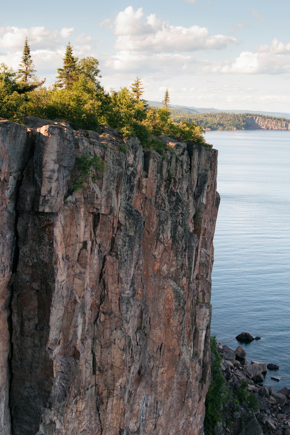 Person, die tagsüber auf einer Felsformation in der Nähe von Gewässern sitzt