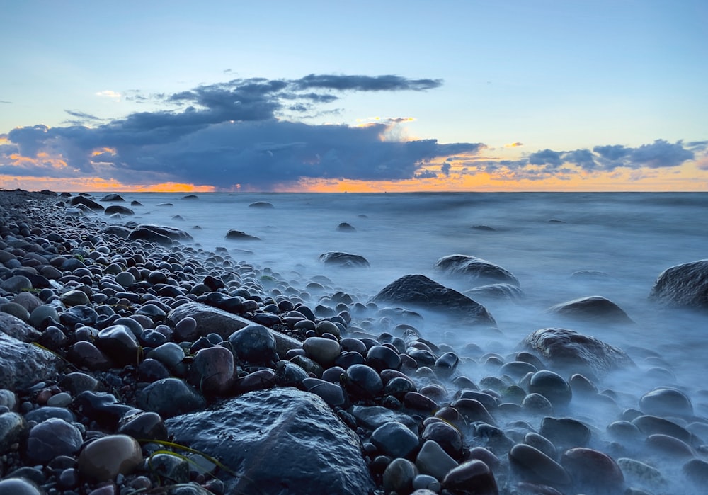 rocky shore with water waves during sunset