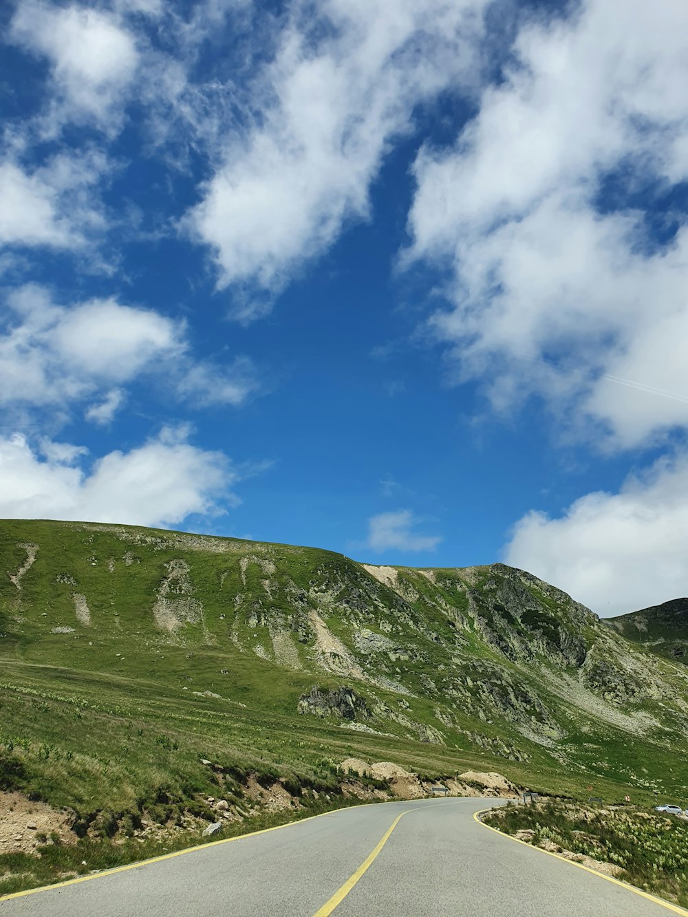 green grass field under blue sky and white clouds during daytime