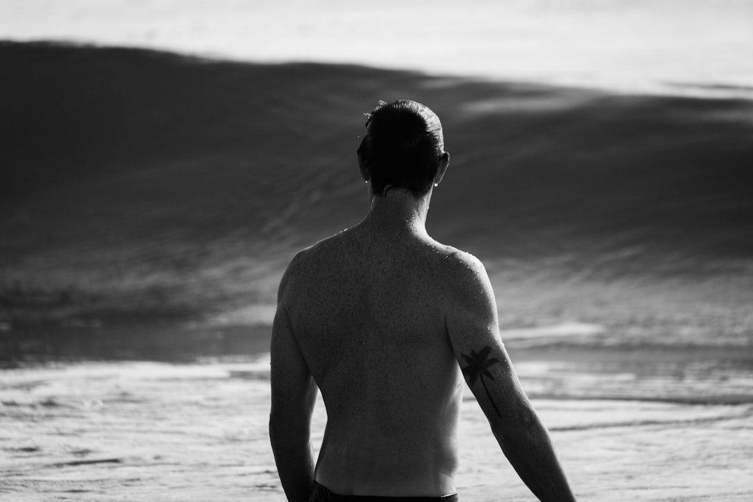 topless man standing on beach