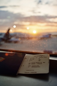 Smiling young traveler holding passport and boarding pass at sunny airport.