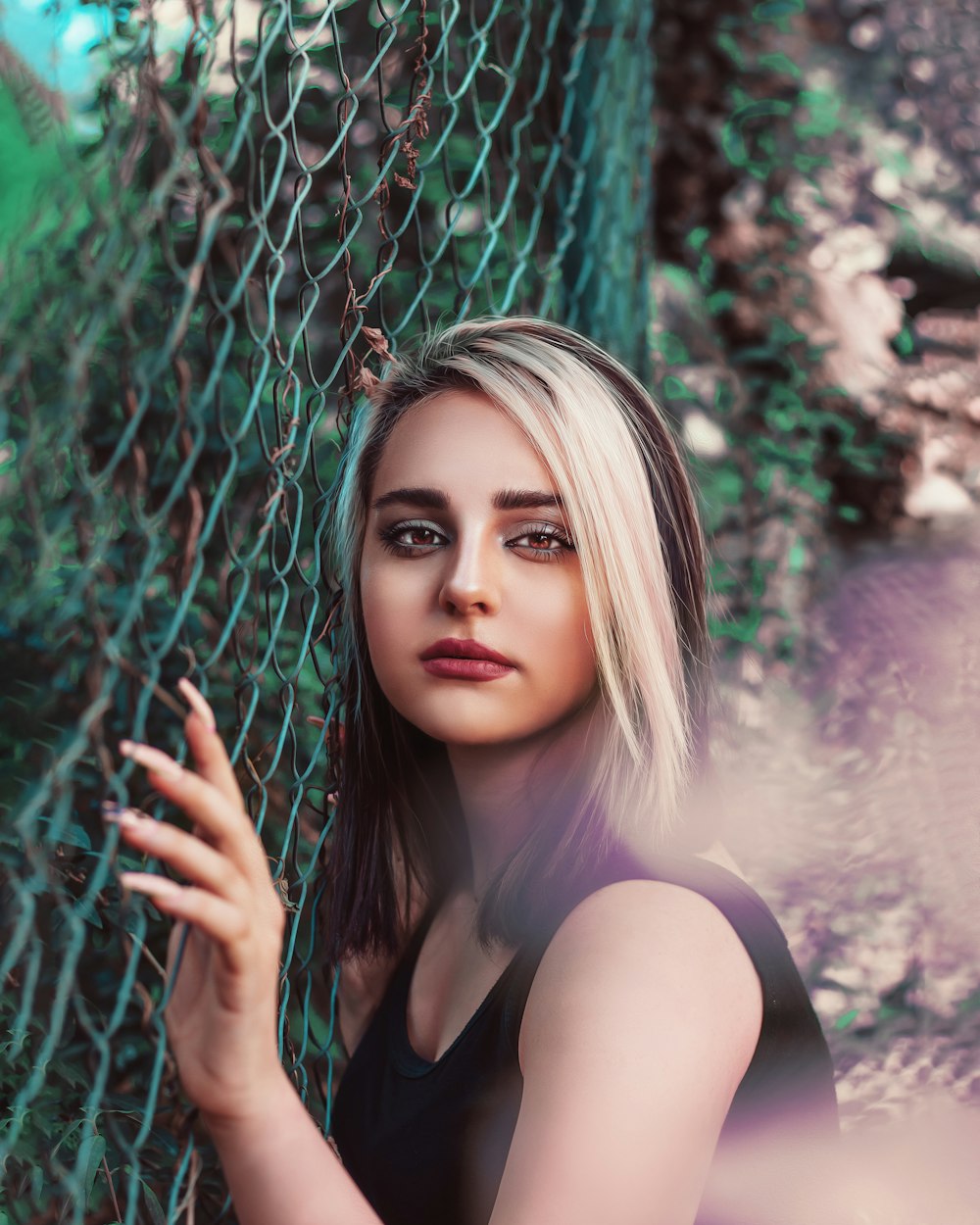 a woman leaning against a chain link fence