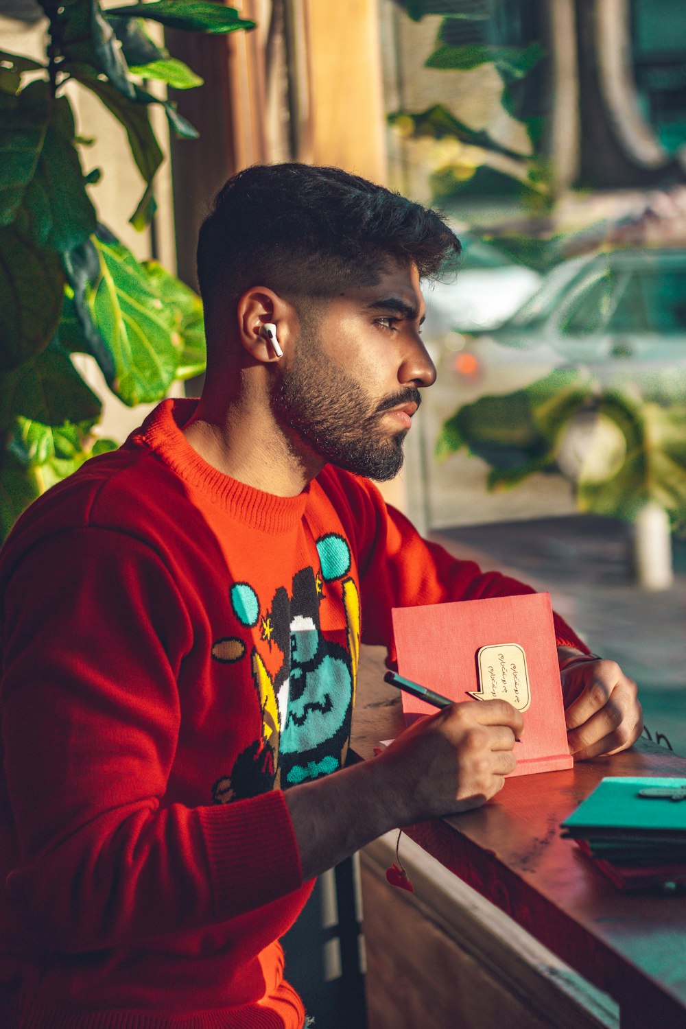 man in red crew neck shirt holding smartphone