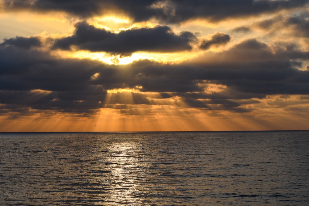 Cuerpo de agua bajo cielo nublado durante la puesta del sol