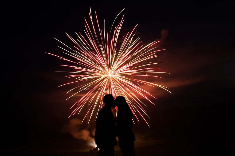 man and woman standing under fireworks during night time