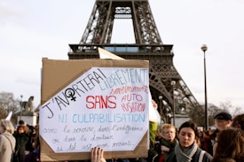 A group of people is gathered in front of the Eiffel Tower, and someone is holding a protest sign with French text advocating for the right to abortion without guilt or permission.