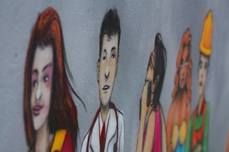 A mural on a wall depicts a series of stylized, colorful illustrations of diverse people in various poses. The characters are drawn with exaggerated features and are painted in a vibrant style. They appear to be lined up, each expressing different emotions or roles.