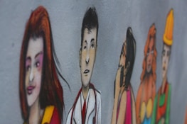 A mural on a wall depicts a series of stylized, colorful illustrations of diverse people in various poses. The characters are drawn with exaggerated features and are painted in a vibrant style. They appear to be lined up, each expressing different emotions or roles.