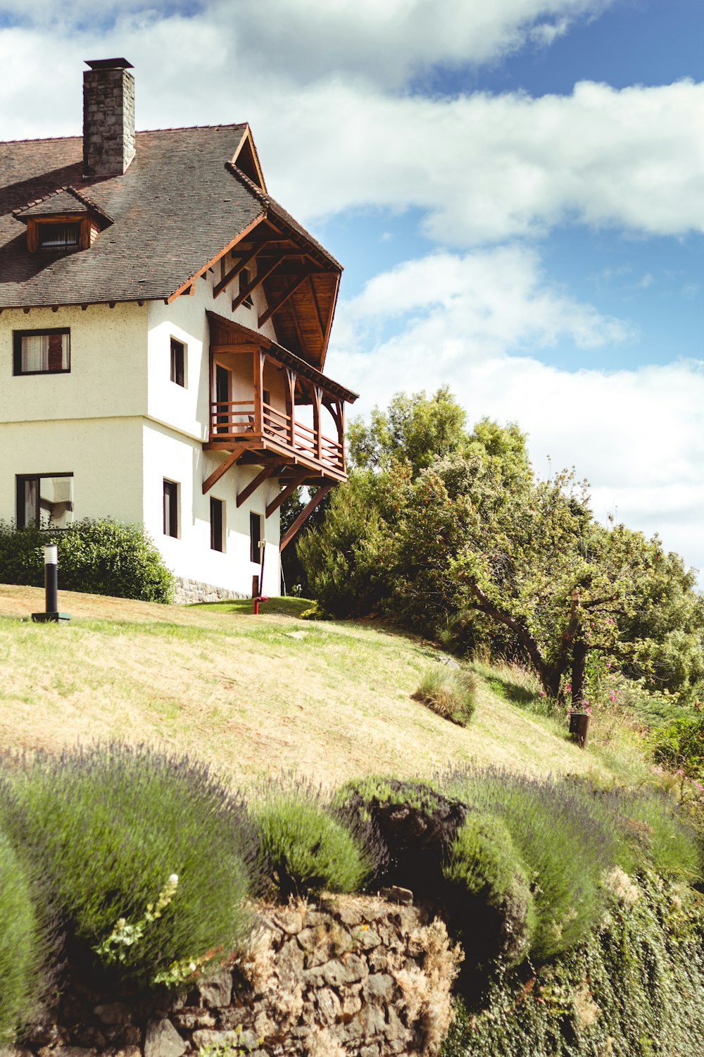 Maison en béton blanc et brun près d’un champ d’herbe verte sous un ciel bleu pendant la journée