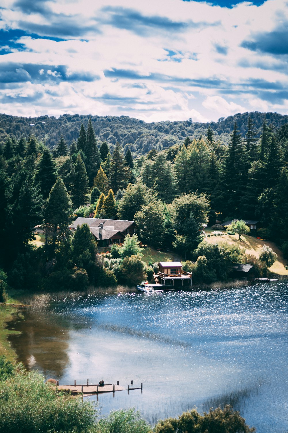 Casa blanca y marrón cerca de árboles verdes y lago durante el día