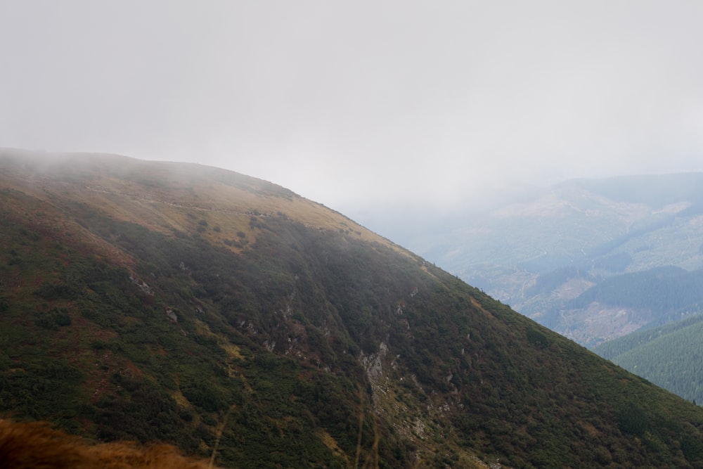 montaña verde y marrón bajo el cielo blanco durante el día