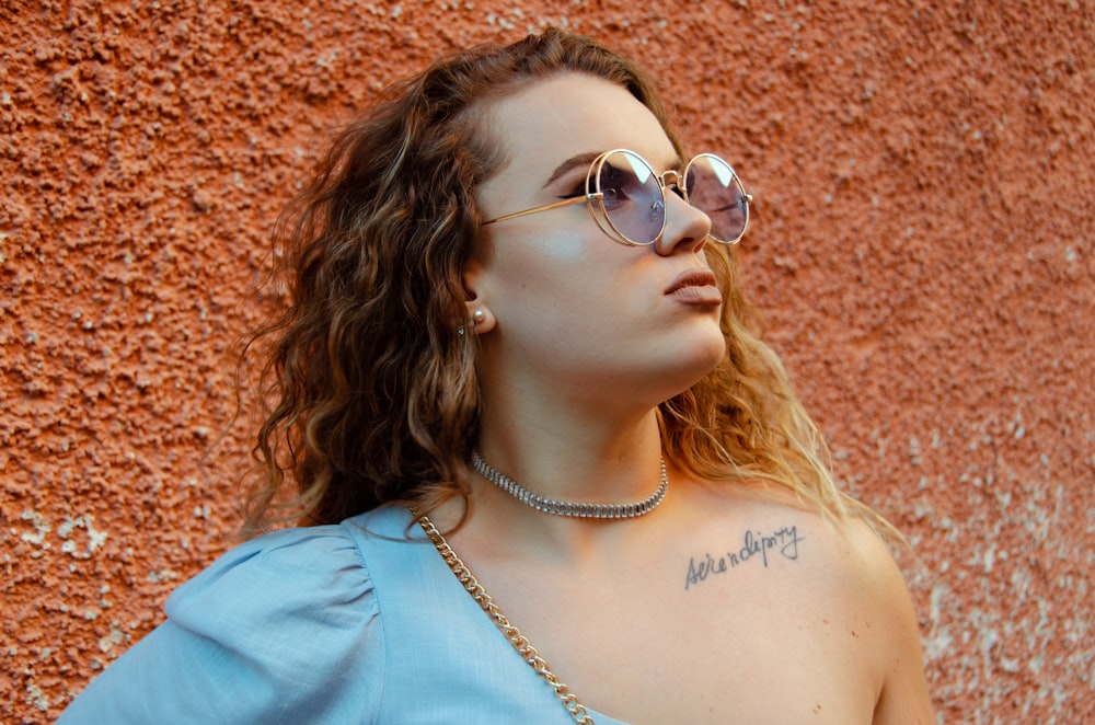 woman in blue shirt wearing silver framed aviator sunglasses