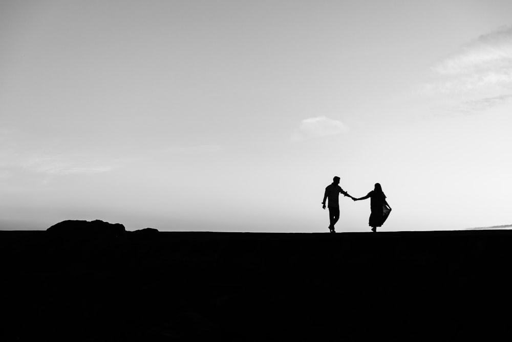 silhouette of 2 person standing on the ground